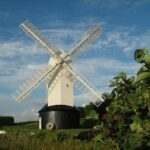 a large white windmill sitting next to a lush green field